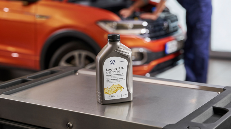 Someone places a bottle of Volkswagen Genuine LongLife III FE Engine Oil in the luggage compartment