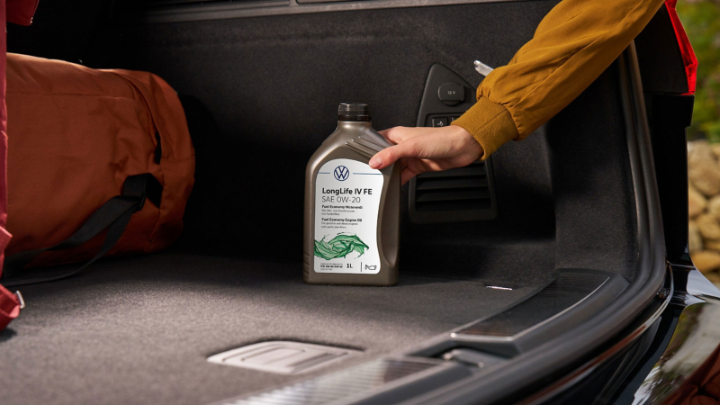 Someone places a bottle of Volkswagen Genuine LongLife IV FE Engine Oil in the luggage compartment
