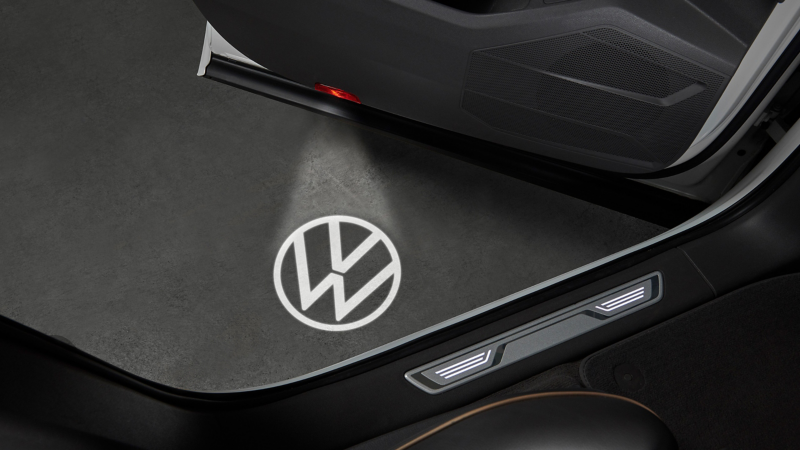 Éclairage d’accueil à LED des Accessoires VW projetant le logo VW sur le sol à côté de la porte conducteur