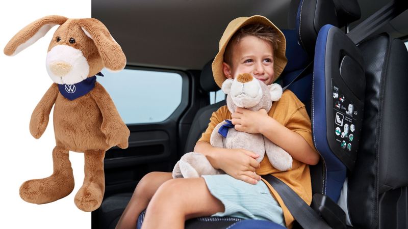VW Plüschhase, im Hintergrund spielt ein Kind im Kindersitz mit einem Kuscheltier