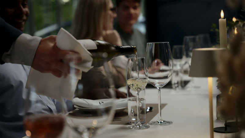 Blick auf Tafel, jemand schenkt Weißwein in ein Glas ein