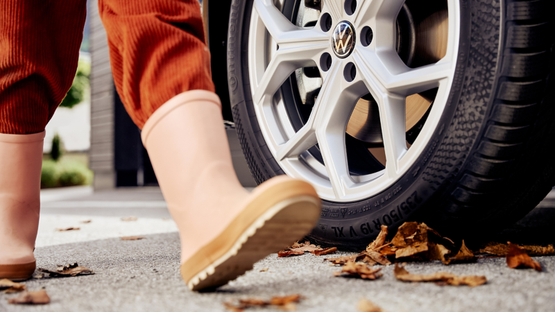 Nahaufnahme einer Person mit Gummistiefeln, die an einem VW Rad vorbeigeht
