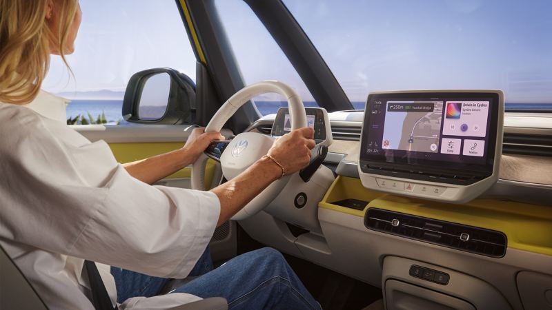A woman sits in the driver’s seat of a VW ID. Buzz and holds the steering wheel in her hand