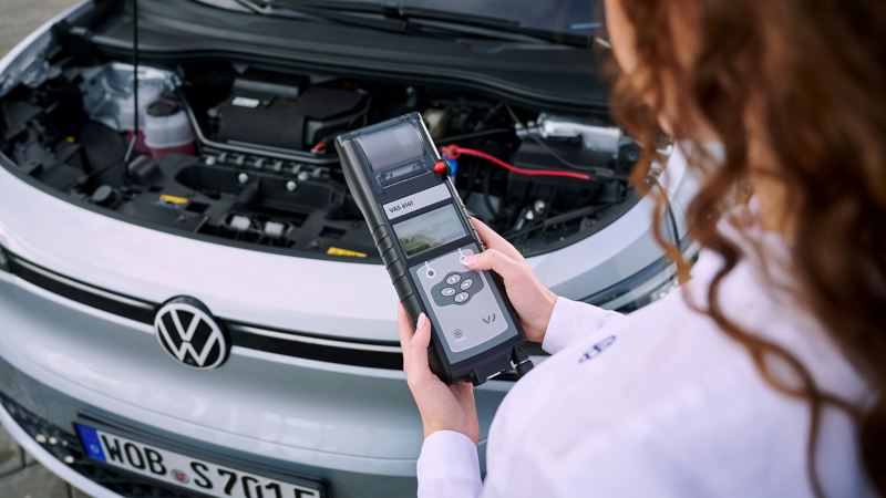 Eine VW Servicemitarbeiterin prüft die Batterie eines Elektroautos