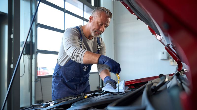 Un employé de l’entretien VW effectue un contrôle de l’huile moteur sur une voiture VW – Vidange VW