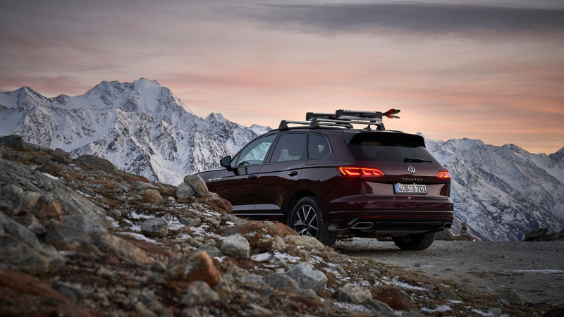 Une voiture Volkswagen roule sur une route de campagne dans les montagnes enneigées