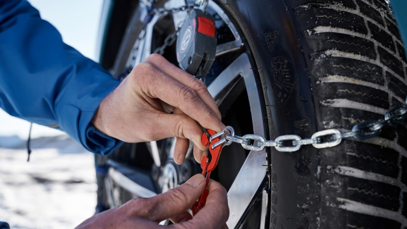 Someone fixates snow chain by Volkswagen Accessories on a Volkswagen tyre