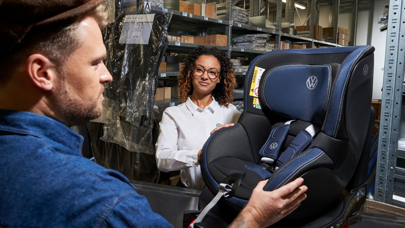 Un employé du service Entretien VW et une cliente observent un siège auto VW