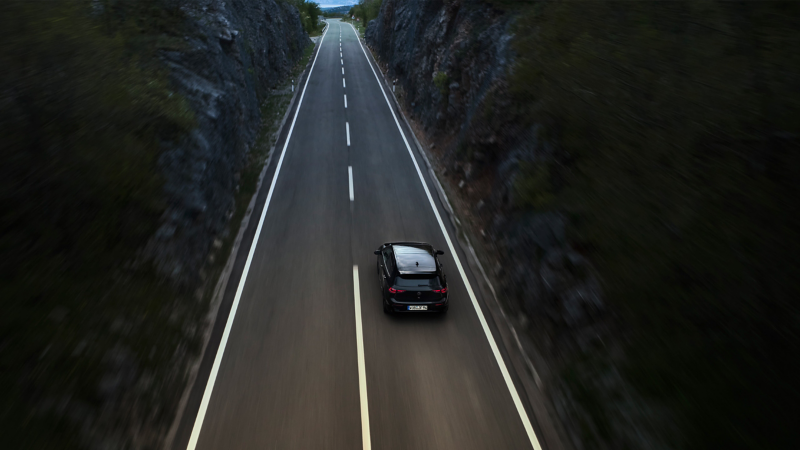 Άποψη από ψηλά ενός VW Golf R Black Edition, το οποίο κινείται σε έναν δρόμο ανάμεσα σε δύο βουνά