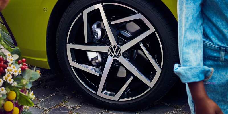 Gros plan sur une jante R-Line de couleur noir et argent, montée sur un pneu, appartenant à une Volkswagen Golf Mk8 jaune.