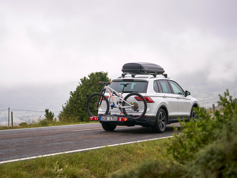 VW Tiguan avec coffre de toit et porte-vélos issus des Accessoires VW sur une route