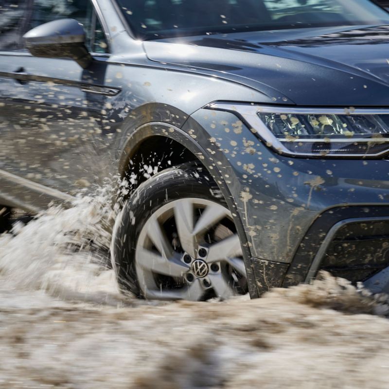 VW rijdt door modder en water, focus op het linkervoorwiel