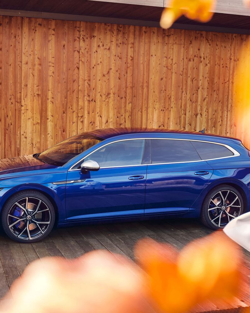 A blue VW Arteon R Shooting Brake parked in front of a wooden wall