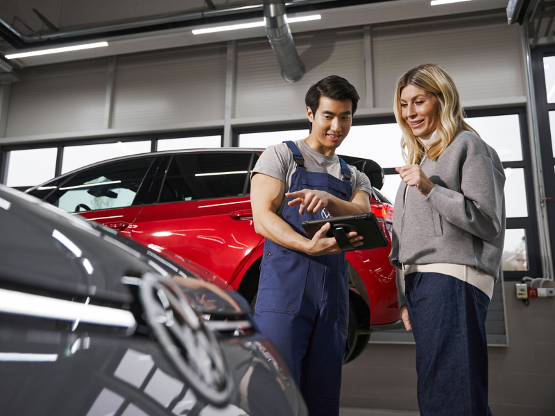 a VW engineer speaking to a customer in a garage