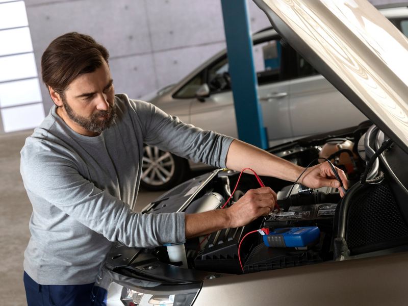 A VW service employee checks the battery inside of a VW car