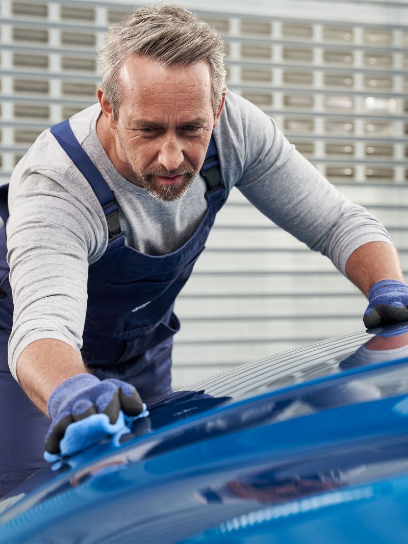 Pracownik serwisu VW pokazuje swojemu klientowi naprawioną karoserię pojazdu – Serwis blacharsko-lakierniczy