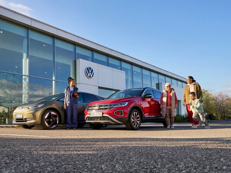 VW dealership, customers at the front and VW service employee next to VW ID.3 and VW T-Roc