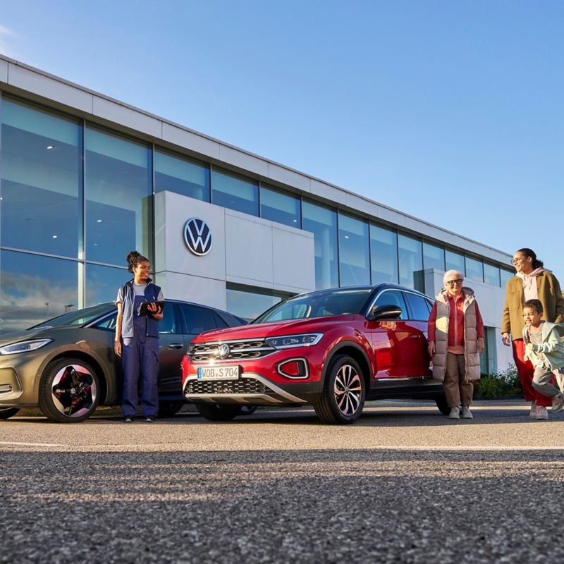 VW dealership, customers at the front and VW service employee next to VW ID.3 and VW T-Roc