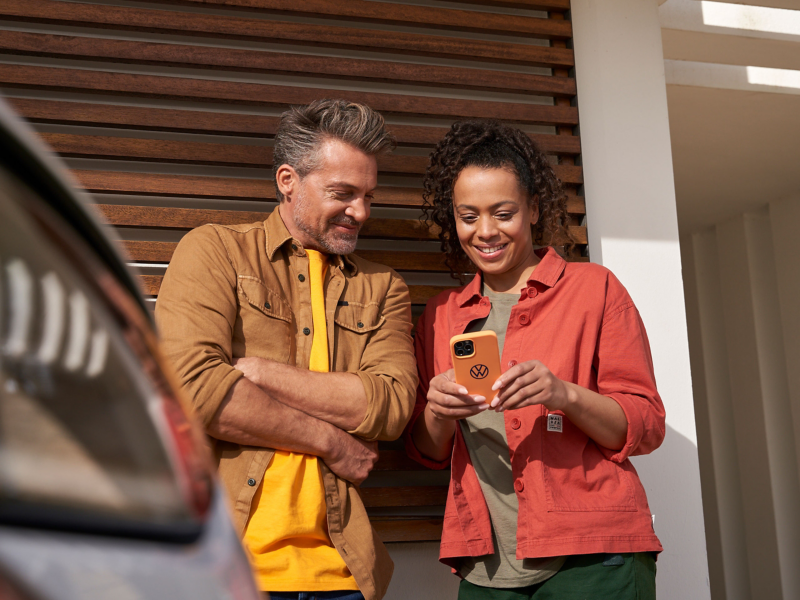 Ένας άνδρας και μία γυναίκα κοιτούν ένα κινητό και χαμογελούν.