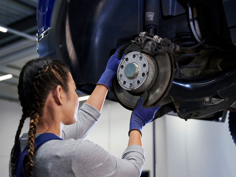 Un empleado del servicio técnico de VW inspecciona el disco de freno de un coche VW