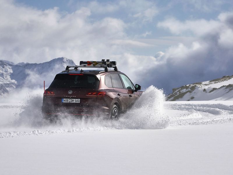 Une VW dérive dans un paysage enneigé, projetant de la neige sur sa course