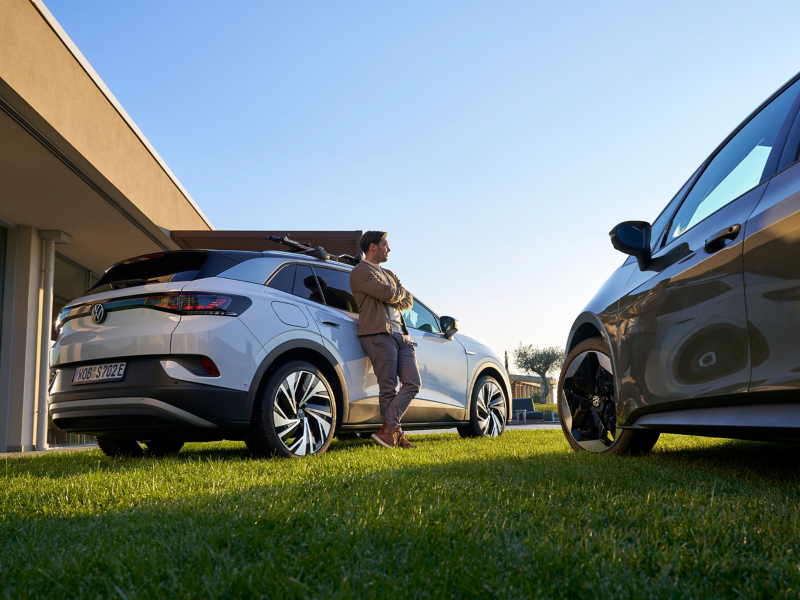 Man leans against a VW ID.4, another VW ID. model in foreground