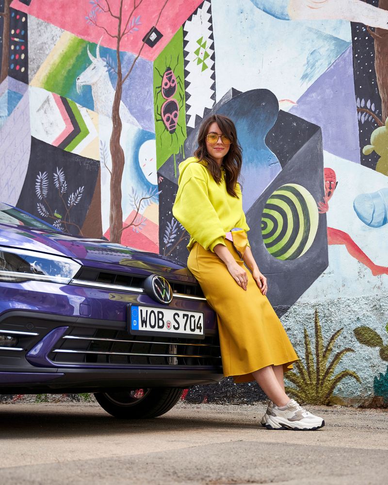 Eine Frau in Gelb steht vor einem VW Polo 6