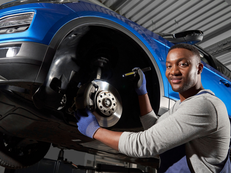 Un employé du service Entretien VW inspecte les freins d’une voiture VW – Entretien Economy
