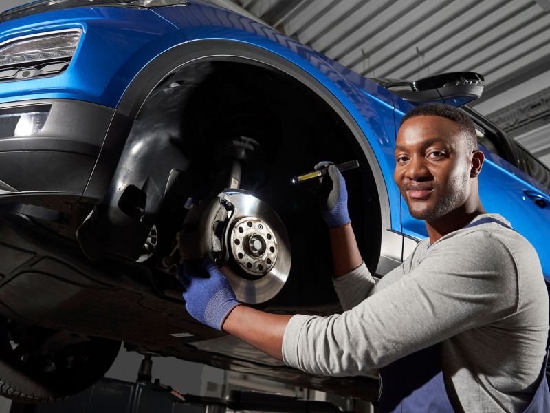 VW service employee inspects the brakes of a VW car – Economy Service