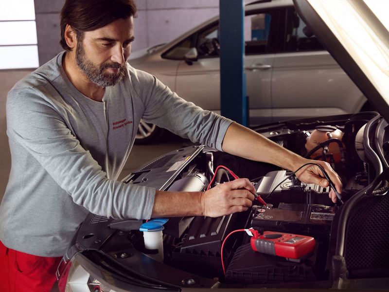 Ένας υπάλληλος service VW ελέγχει την μπαταρία ενός αυτοκινήτου κατά τη διάρκεια ενός Economy Service