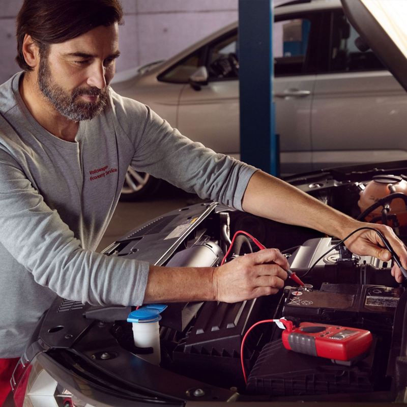 A VW service employee checks the battery of a car during an Economy Service