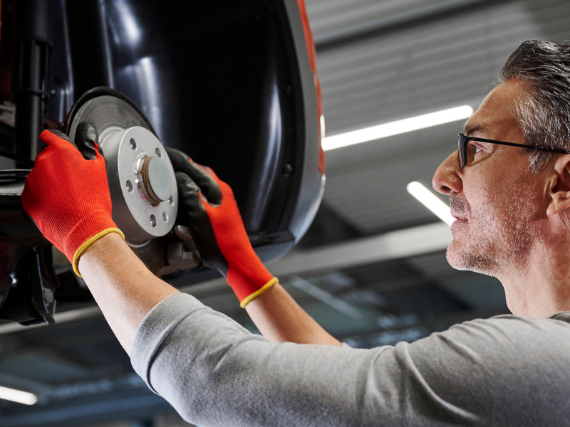 VW service employee inspects the brake system of a VW car