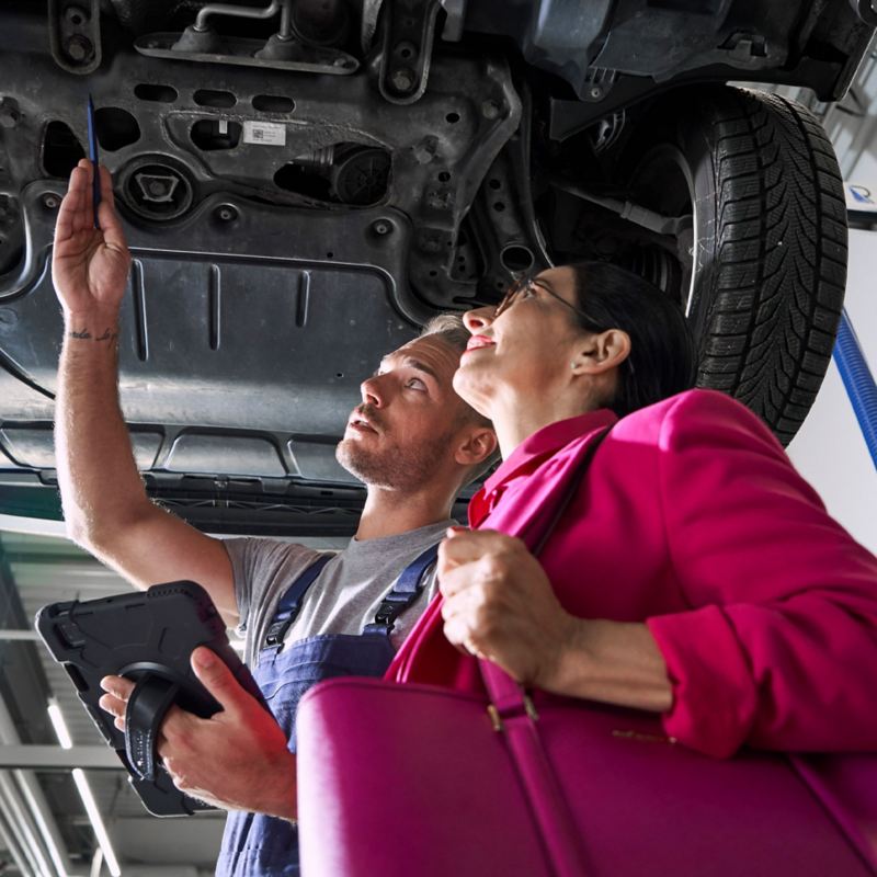 VW service employee and customer look at the underfloor of a VW car