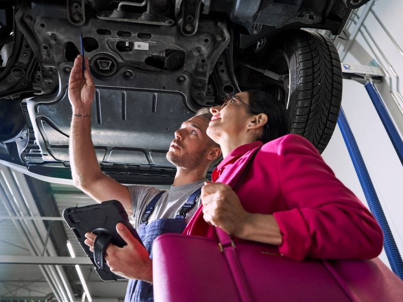 VW-servicemedewerker en klant kijken naar het onderstel van een VW