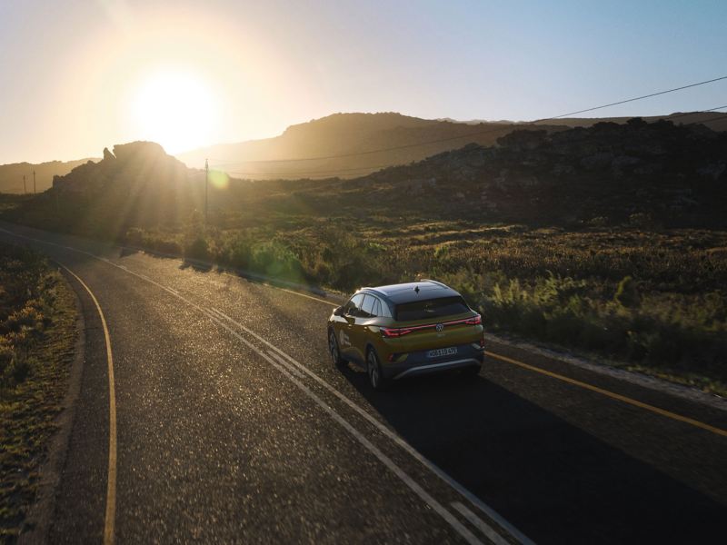 Ein Auto fährt im Licht der untergehenden Sonne auf einer Straße – Abenteuer im Volkswagen