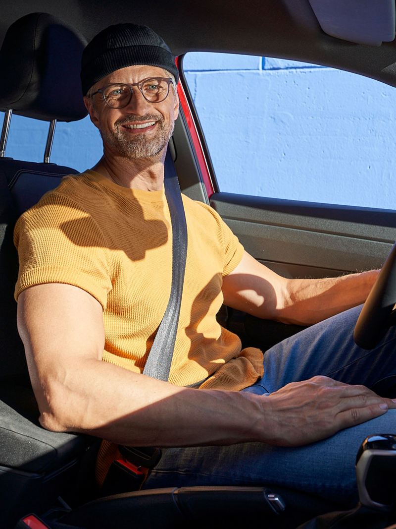 A man sits at the steering wheel of a VW car and looks forward to his Driving Experience Tour – Experience Days