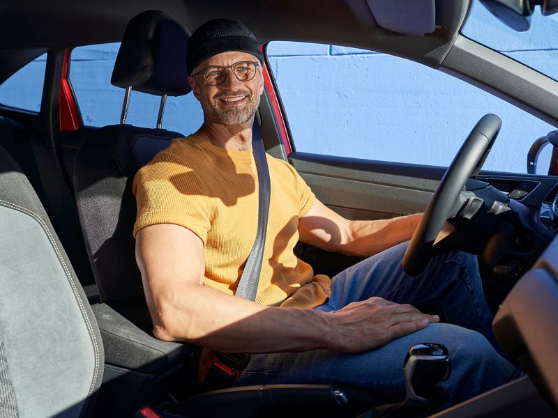 Ein Mann sitzt am Steuer eines VW Autos und freut sich auf seine Driving Experience Tour – Experience Days