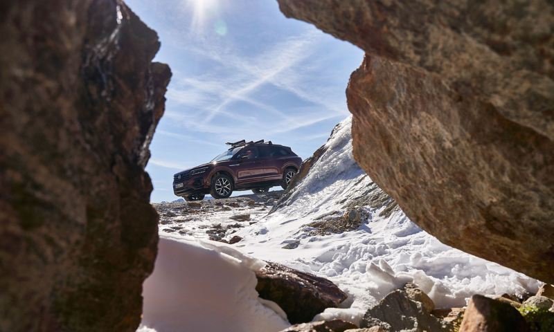 Un SUV de Volkswagen en una carretera nevada visto entre unas rocas