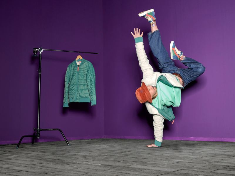 Mann mit Wendejacke aus der ID. Buzz Kollektion macht einarmigen Handstand – VW Fanartikel