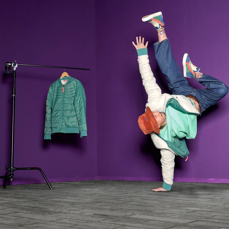 Mann mit Wendejacke aus der ID. Buzz Kollektion macht einarmigen Handstand – VW Fanartikel