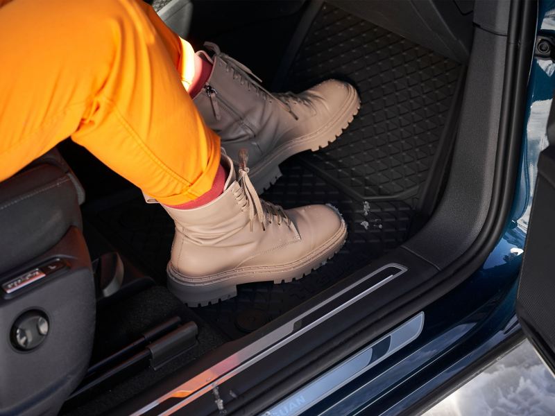 A snowy hiking boot on Volkswagen Accessories Rubber floor mats in a VW Touareg
