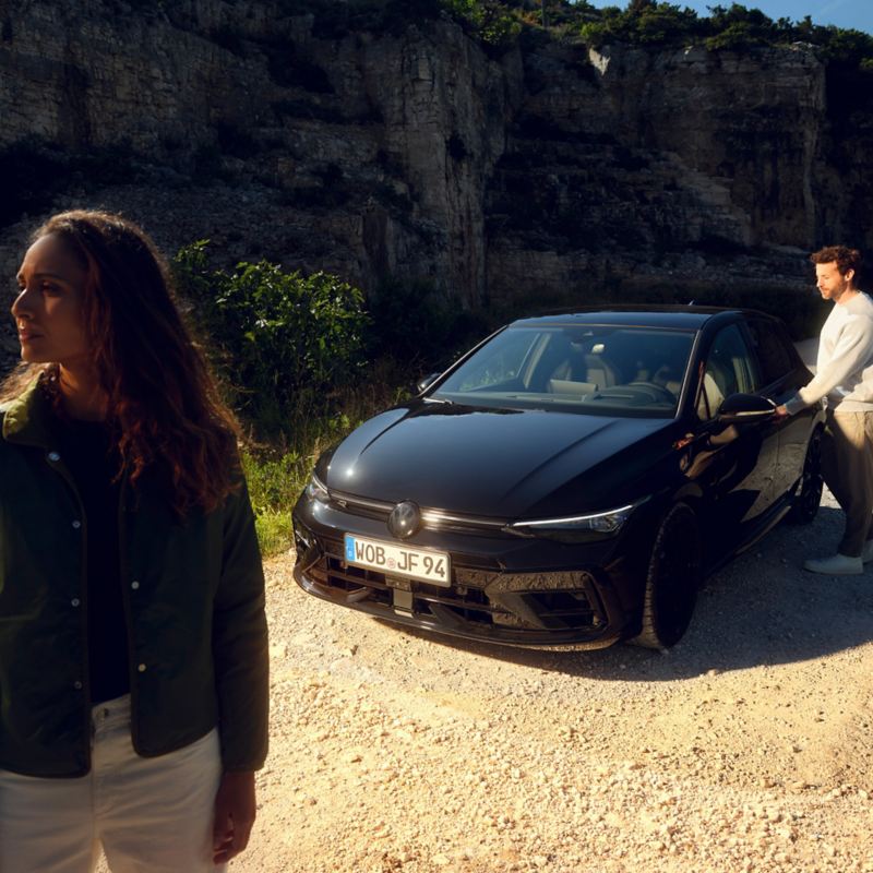 Mann an Fahrertür eines VW Golf R Black Edition, im Vordergrund eine Frau