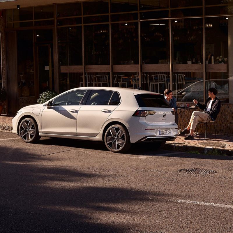 Zwei Männer sitzen neben parkendem VW Golf