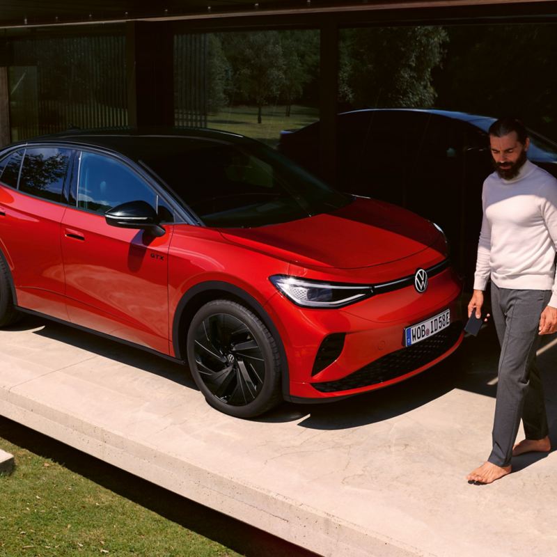 Roter VW ID.5 GTX in einem modernen Carport, ein Mann geht vor der Motorhaube entlang