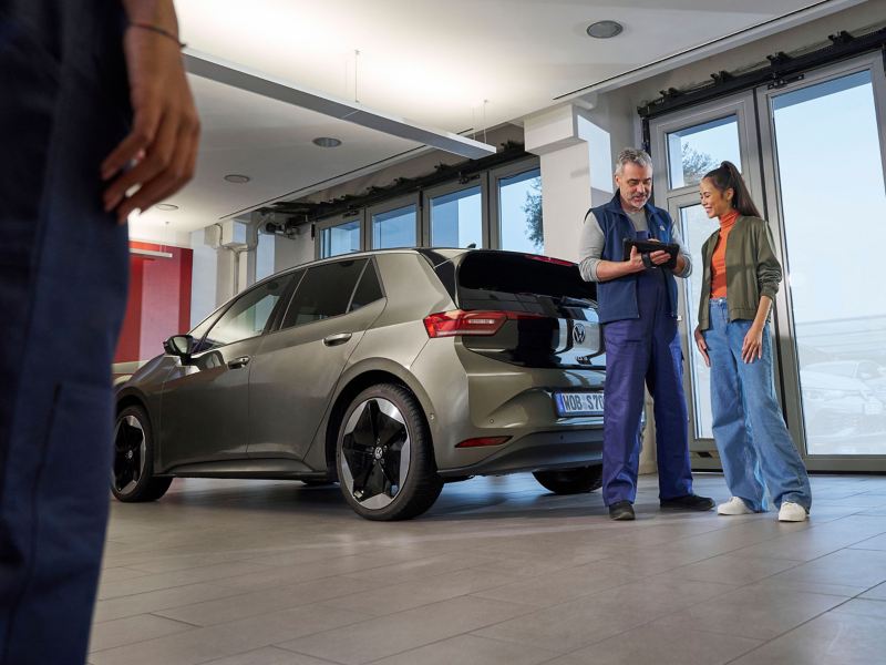 VW service employee and customer next to VW ID.3 looking at a tablet