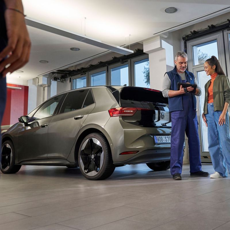 VW service employee and customer next to VW ID.3 looking at a tablet