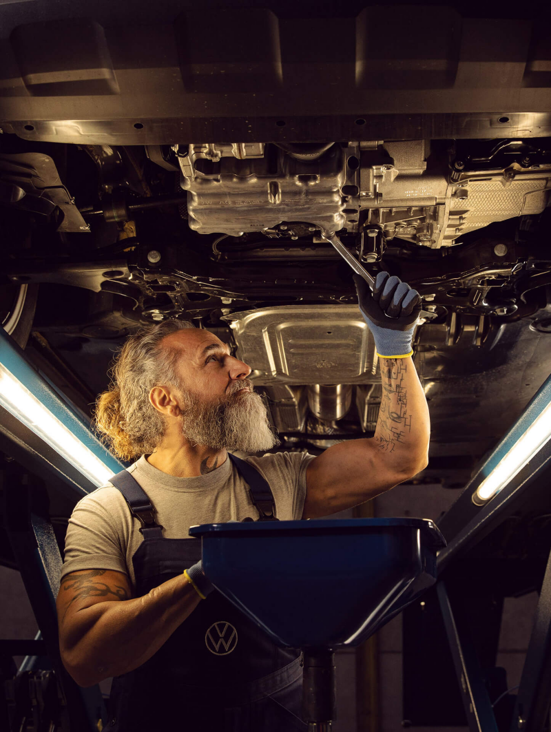 Monteur sleutelt aan het onderstel van een Volkswagen bedrijfsvoertuig