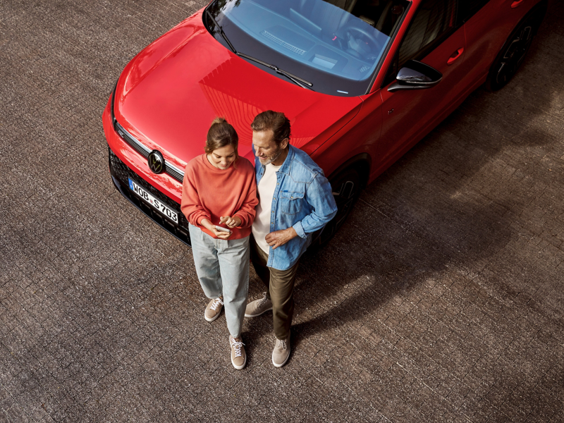 Mann und Frau an einem VW Auto aus der Vogelperspektive