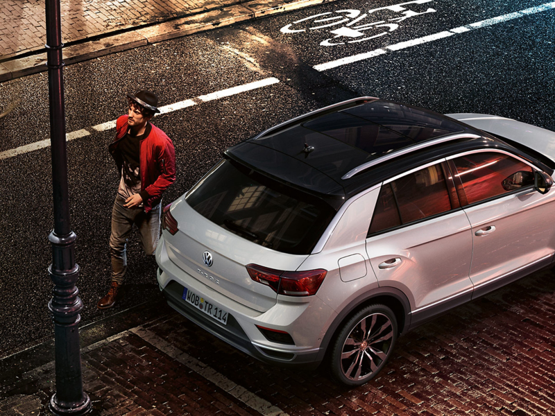 Mann mit Hut steht neben VW T-Roc – VW Leasing