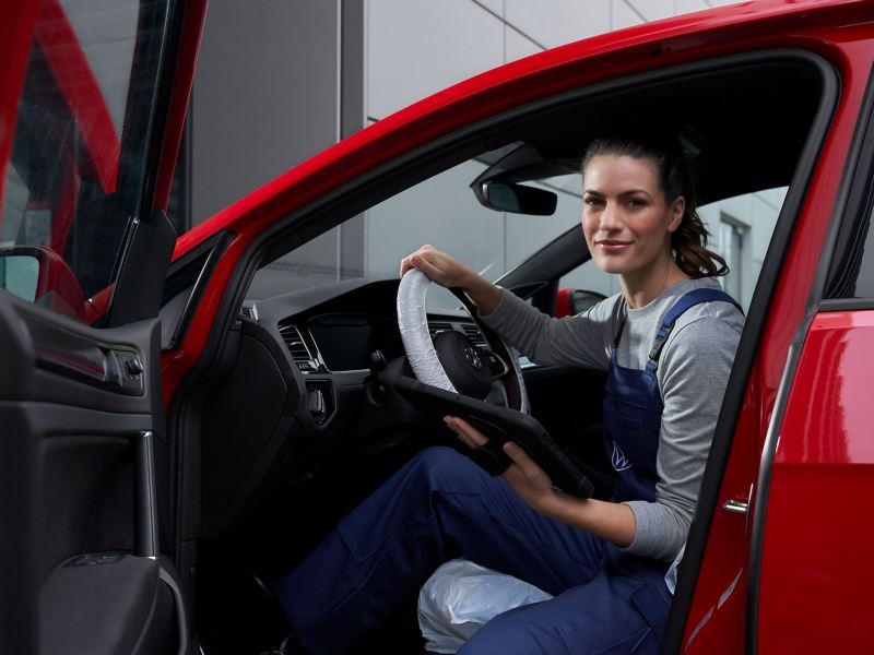 A service employee sits in a red VW during an inspection